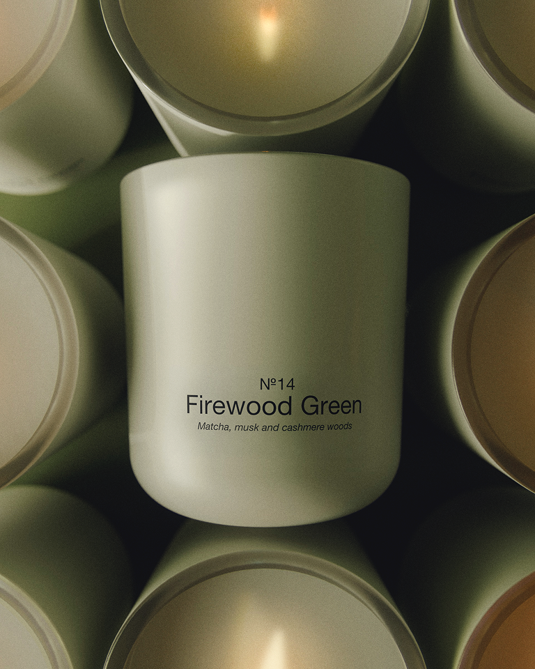 Marie-Stella-Maris No. 14 Firewood Green scented candle surrounded by softly lit candle vessels, featuring notes of matcha, musk and cashmere woods.
