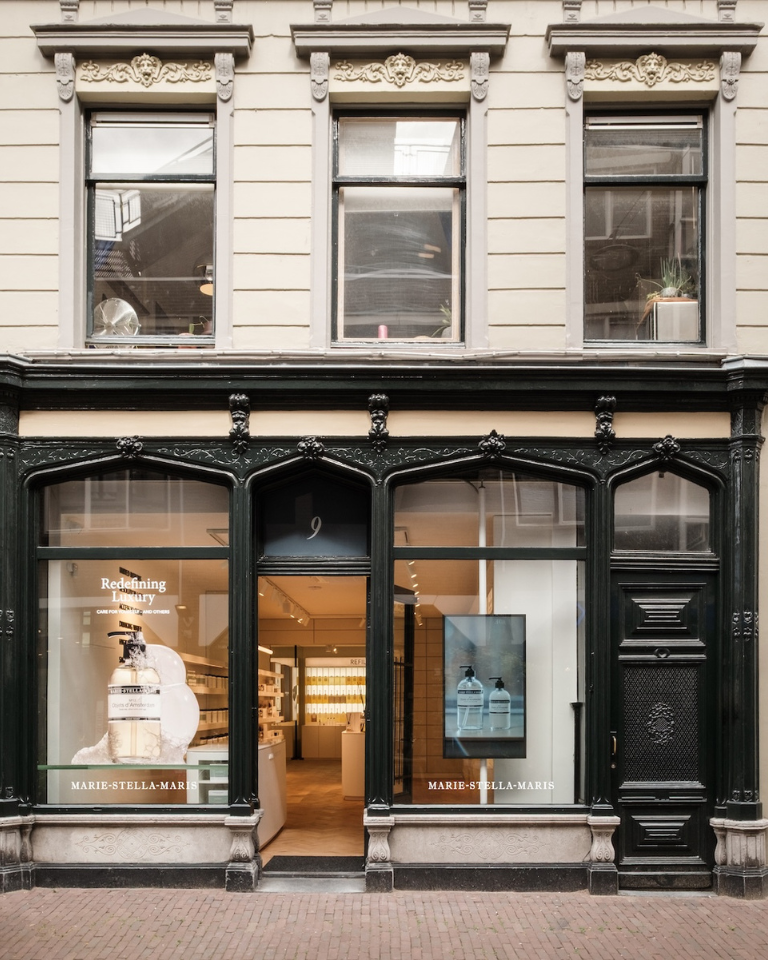 Front of the Marie-Stella-Maris store in Arnhem: historic facade with dark ornamental frames, two large windows showing product displays and a warmly lit interior.