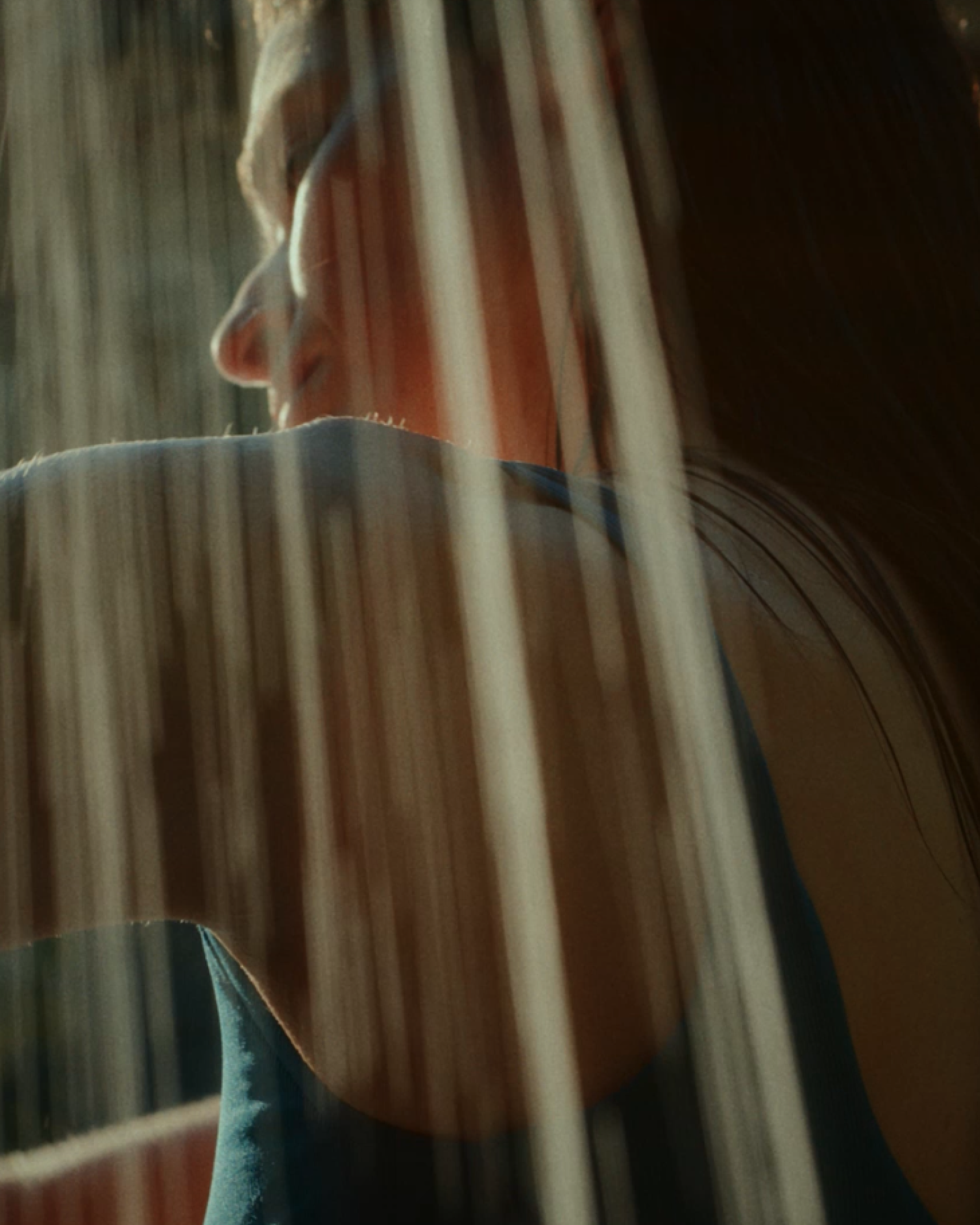 Close-up of a person enjoying an outdoor shower, with water cascading through the sunlight at Cala Deià, Mallorca.