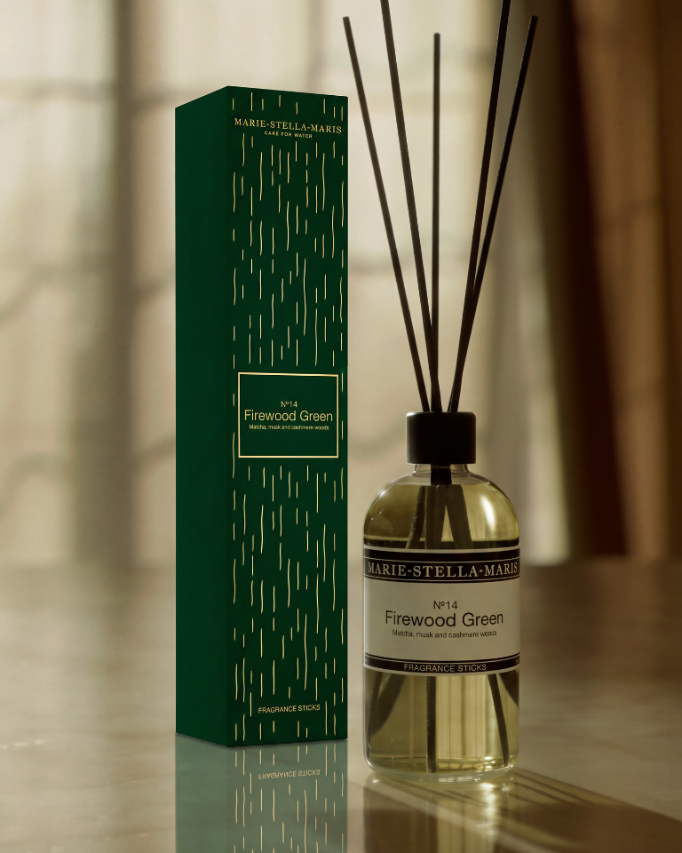 Marie-Stella-Maris No. 14 Firewood Green fragrance diffuser with black reeds, displayed in warm sunlight beside its festive dark green and gold gift box.