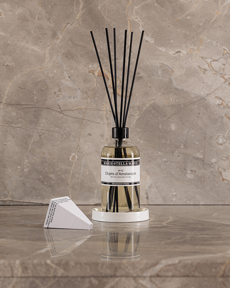 Marie-Stella-Maris Fragrance Sticks No.12 Objets d’Amsterdam 250 ml in a clear glass bottle with black reeds, placed on a marble surface with matching stone background and packaging detail.