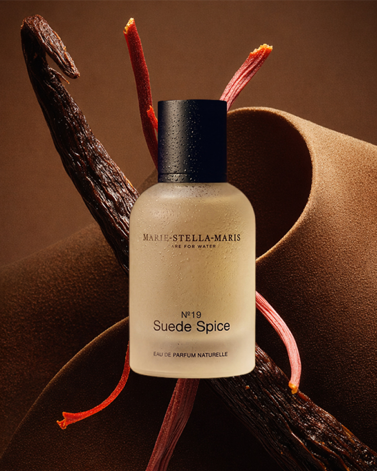 Marie-Stella-Maris suede spice perfume with brown background and water droplets on bottle