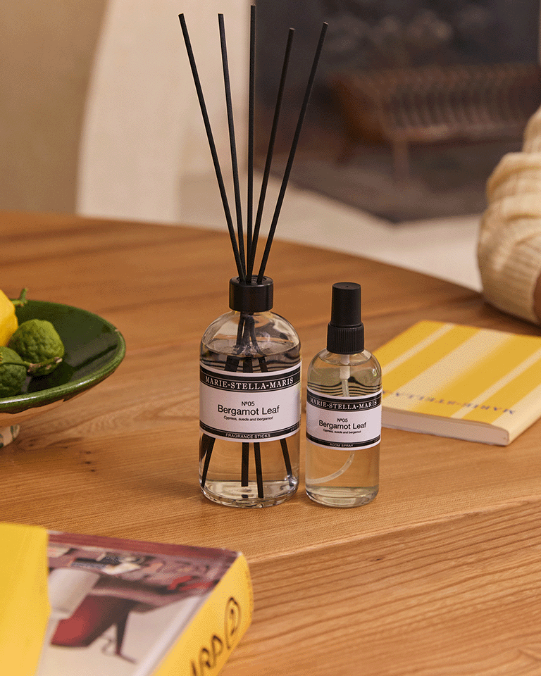 Marie-Stella-Maris fragrance sticks 250 ml and Room Spray 100 ml in the No.05 Bergamot Leaf scent, on a wooden table, styled with citrus fruits, books, and warm-toned decor in the background.