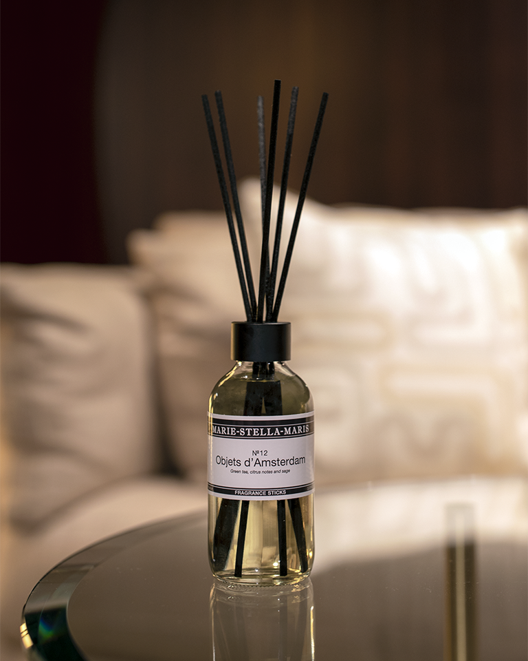 Marie-Stella-Maris Luxury fragrance sticks No.12 Objets d'Amsterdam 100 ml with green tea, citrus, and sage scent on a glass table with a white couch in the background