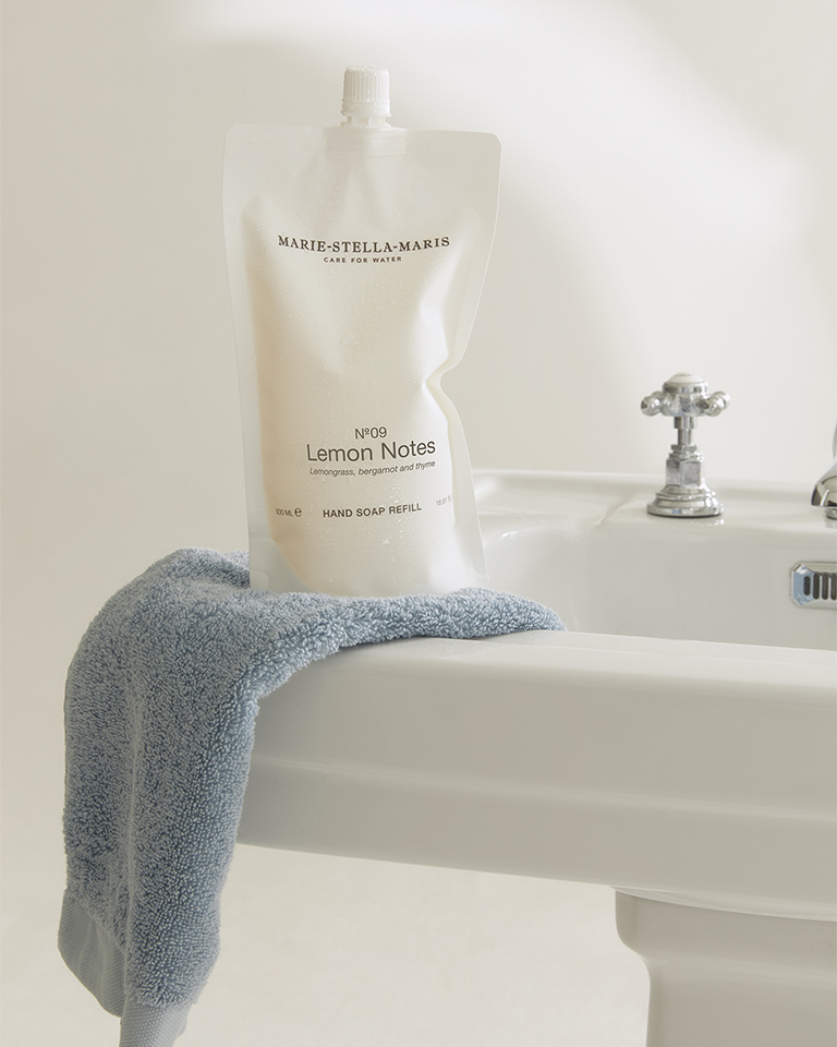 Marie-Stella-Maris No.09 Lemon Notes hand soap refill pouches 500 ml on a white bathroom sink with chrome taps with a blue towel.