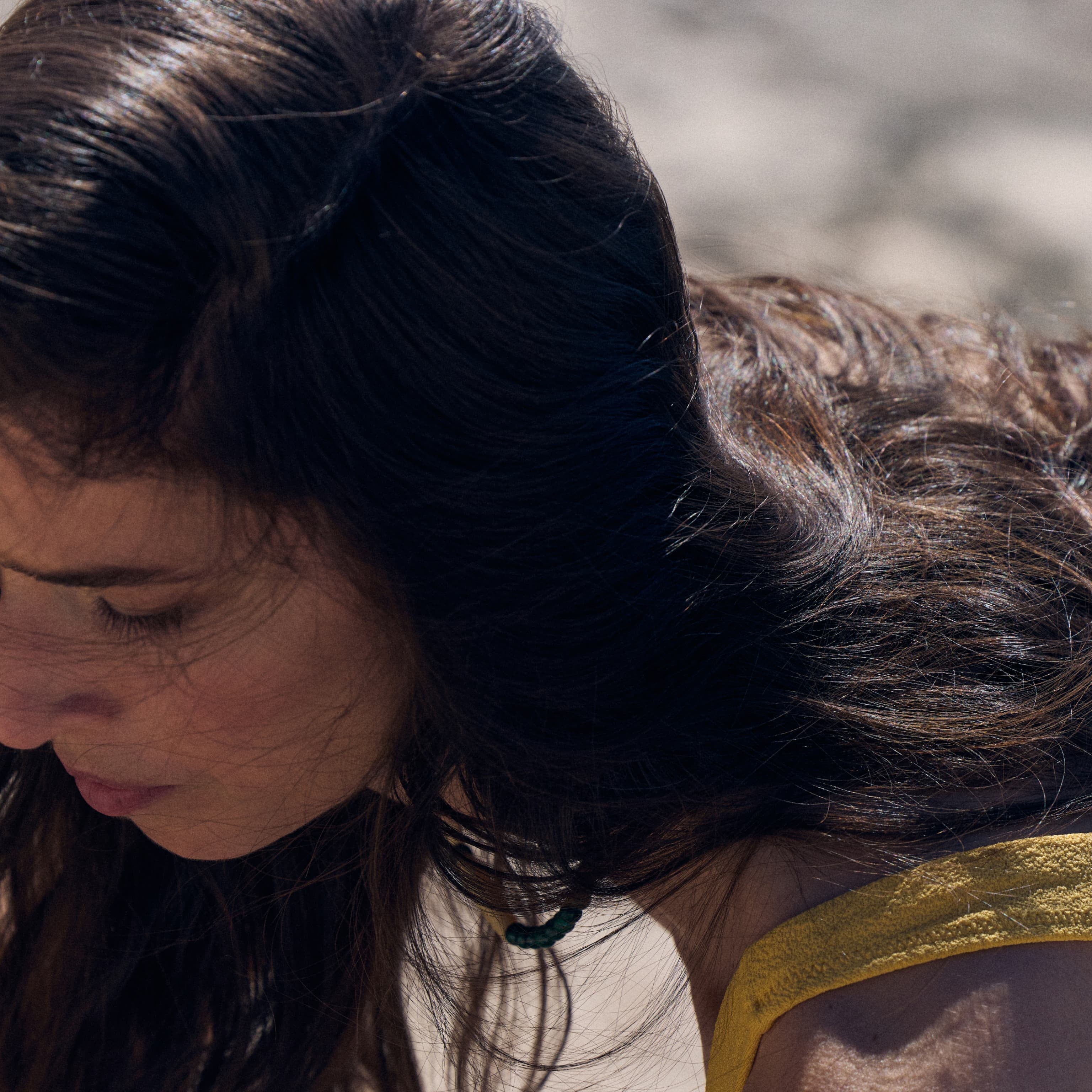 Close-up of a person in a sunlit outdoor setting wearing a yellow swimsuit, creating a warm, summery mood image to support the Marie-Stella-Maris May gift with purchase campaign.