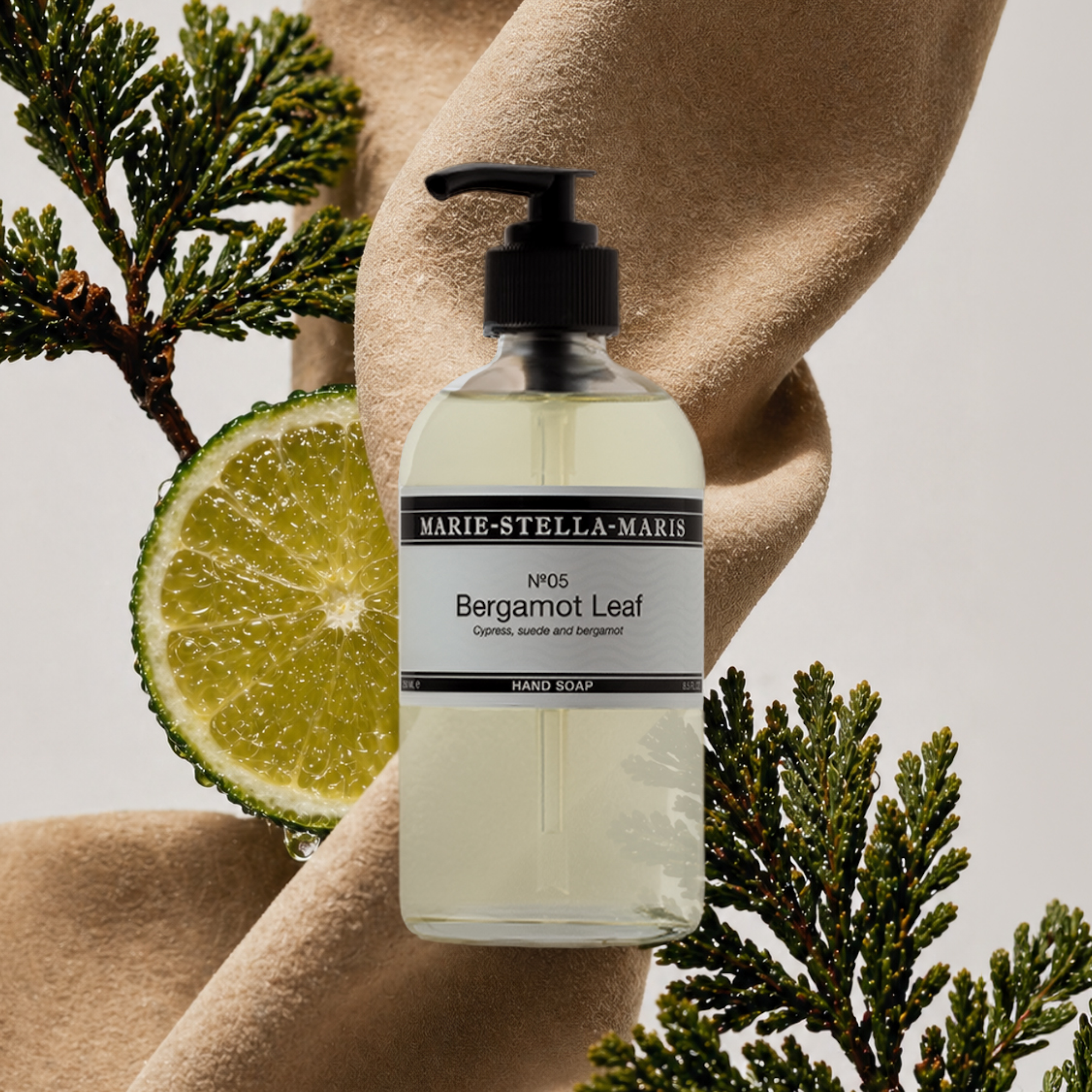 Marie-Stella-Maris No.05 Bergamot Leaf limited edition summer scent hand soap, styled with fresh bergamot and cypress branches against soft textured fabric, highlighting the fragrance notes of cypress, suede, and bergamot.