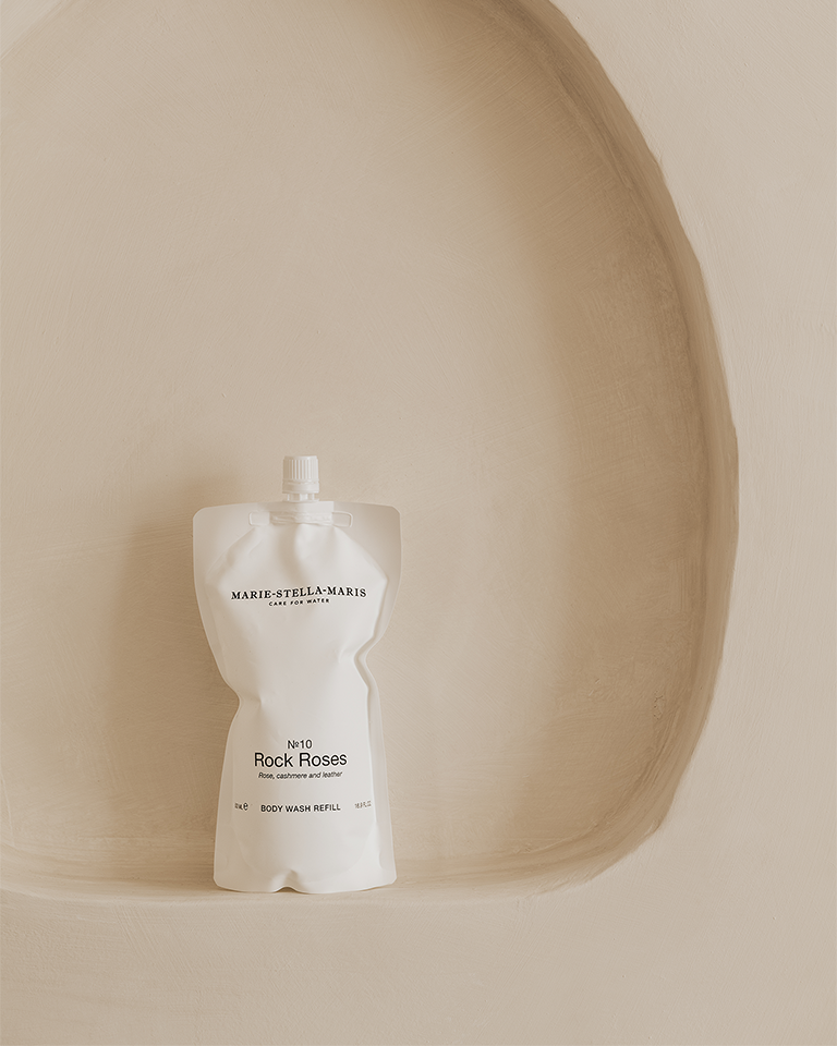 500 ml rock roses body wash refill pouch standing on a curved beige textured surface background