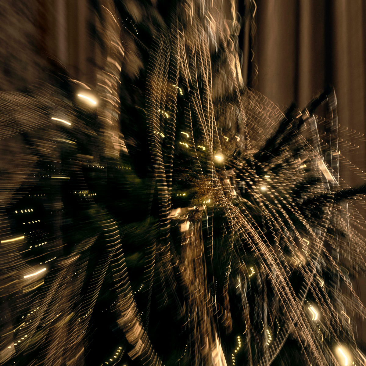 Golden holiday lights streak through a dark city scene at night, creating a sense of motion.