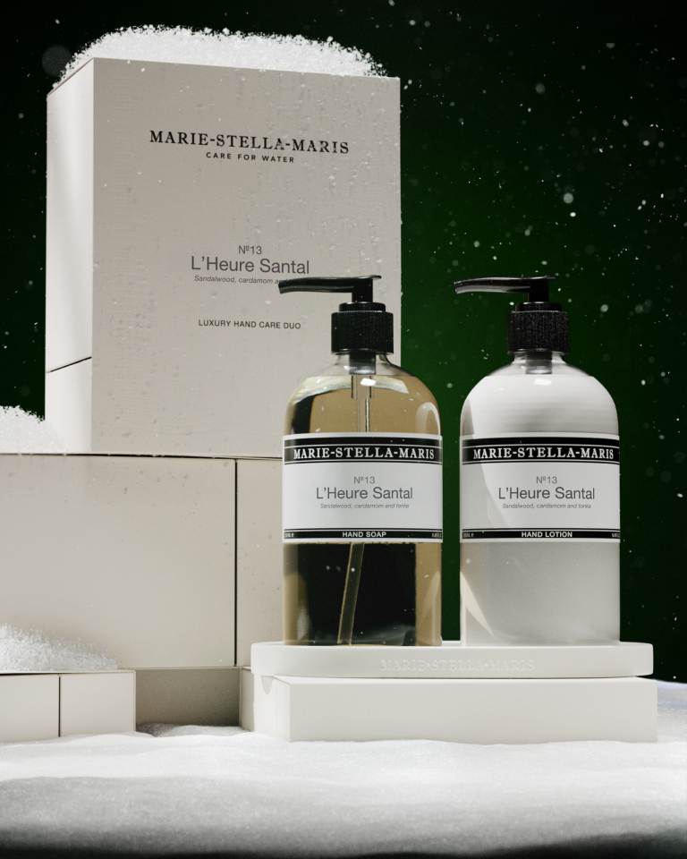 Marie-Stella-Maris No.13 L’Heure Santal Luxury Hand Care Duo on a white tray beside its gift box, surrounded by snow against a dark green festive backdrop.