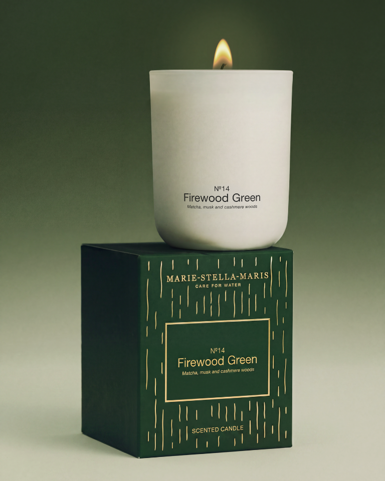 Lit Marie-Stella-Maris No. 14 Firewood Green scented candle displayed on its festive dark green and gold gift box, featuring notes of matcha, musk and cashmere woods.
