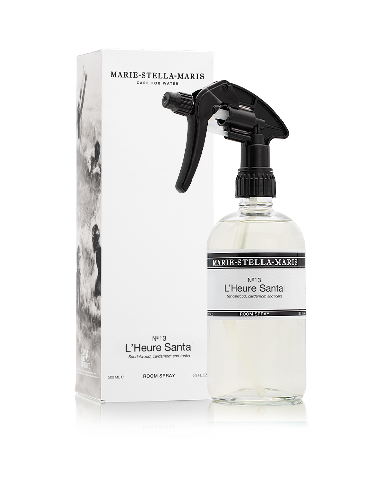 Marie-Stella-Maris Room Spray in No.13 L’Heure Santal, presented in a clear glass spray bottle with a black trigger spray alongside its white product box. The signature fragrance features notes of sandalwood, cardamom and tonka, photographed against a clean white background.