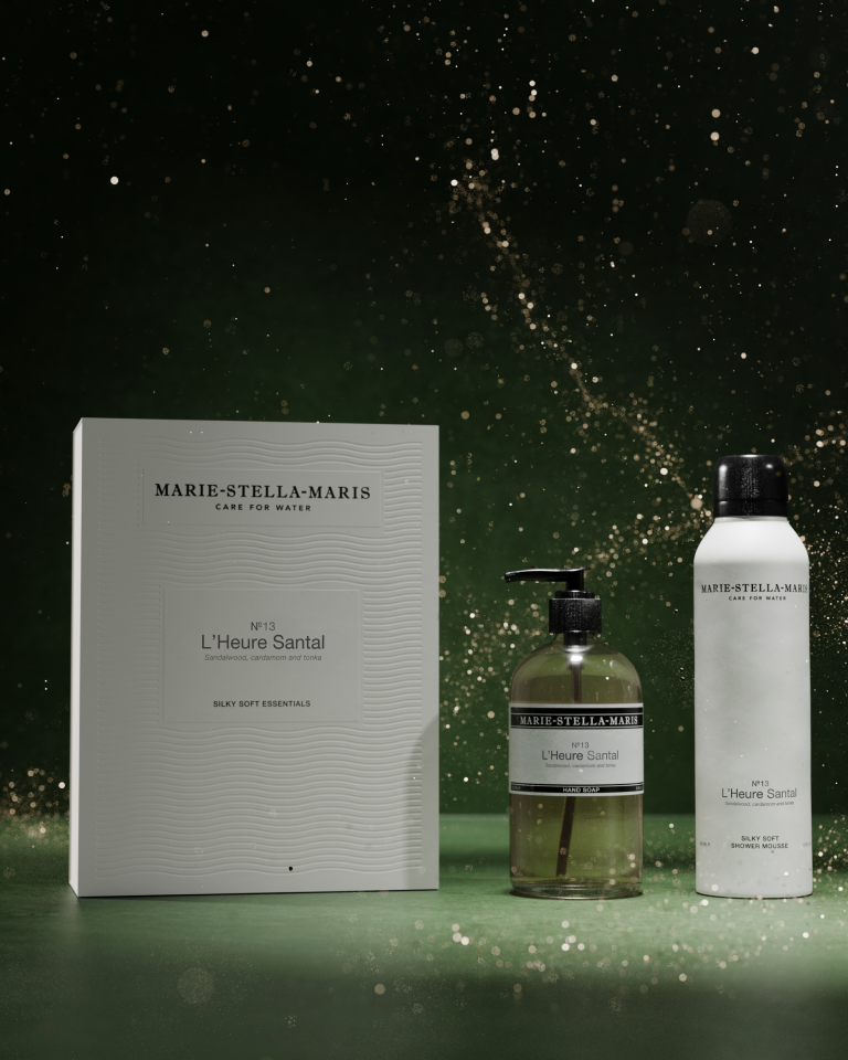 Marie-Stella-Maris No.13 L’Heure Santal Silky Soft Essentials gift set, with hand soap and shower mousse against a festive dark green background with gold sparkles.