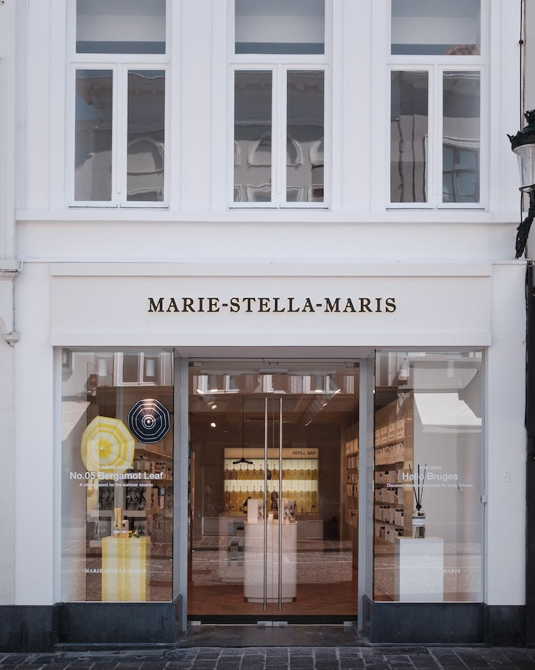 Exterior of the Marie-Stella-Maris boutique in Bruges, featuring a white historic façade, large storefront windows, and the Marie-Stella-Maris logo above the entrance.
