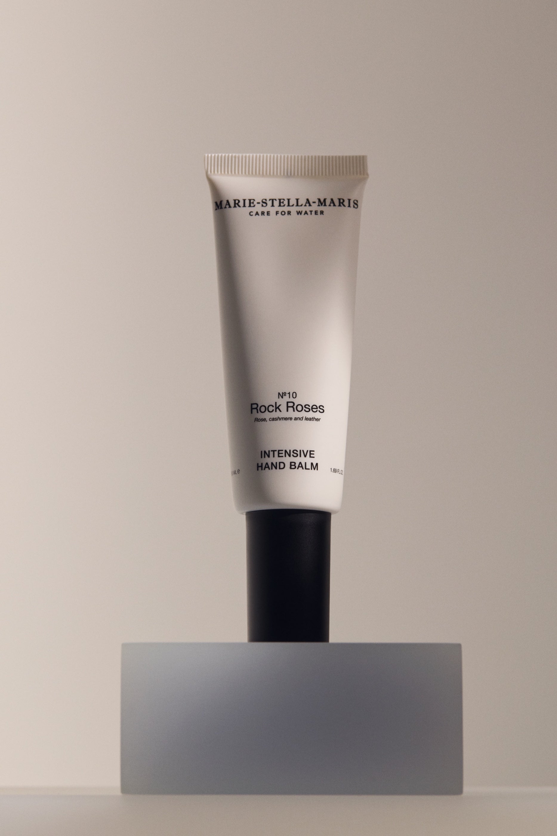 Marie-Stella-Maris Intensive Hand Balm No.10 Rock Roses 50 ml displayed on a minimalist pedestal, featuring a sleek white tube with a black cap against a soft neutral background.
