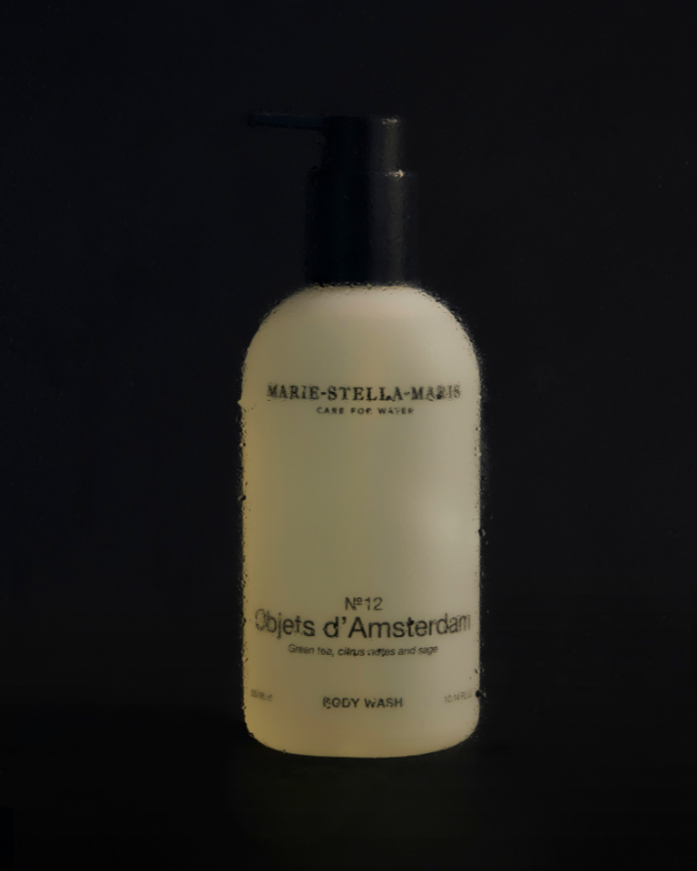 Marie-Stella-Maris Body Wash No.12 Objets d’Amsterdam 300 ml in a minimalist white bottle with black pump, softly lit against a dark background with water drops.