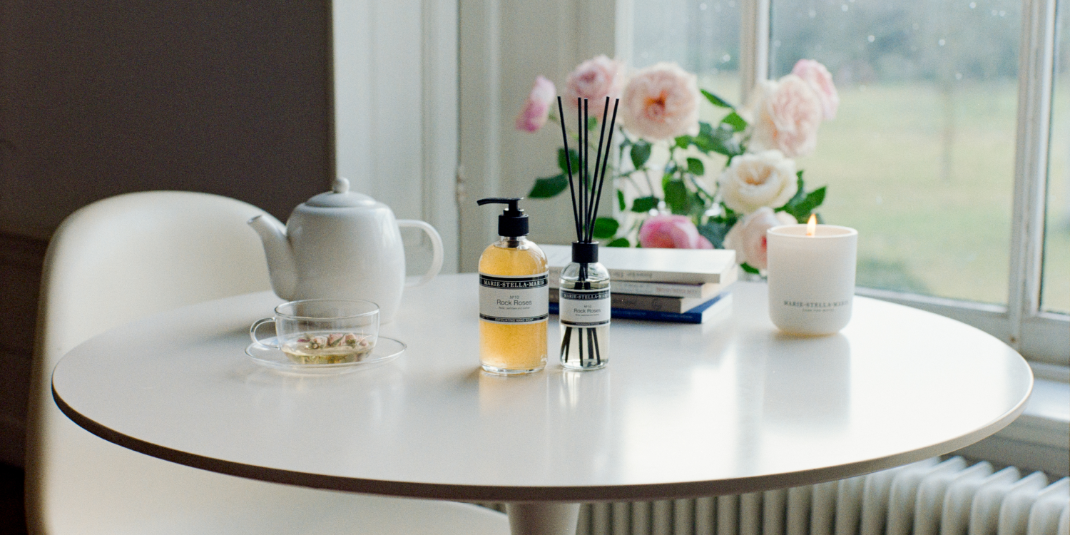 Marie-Stella-Maris Rock Roses hand soap fragrance sticks and scented candle on a table with pink flowers
