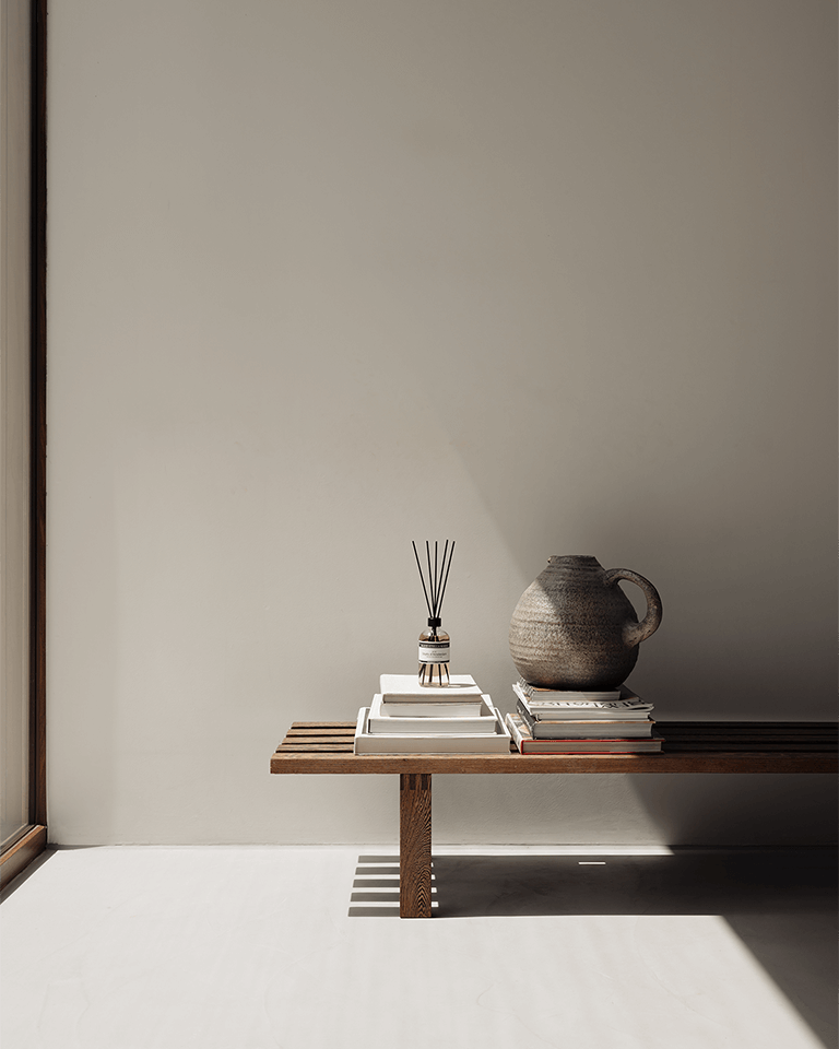 Marie-Stella-Maris Fragrance Sticks No.12 Objets d’Amsterdam 500 ml displayed on a minimalist wooden bench, set on a stack of neutral books beside a textured ceramic jug, with soft natural light and subtle shadows against a warm beige wall.