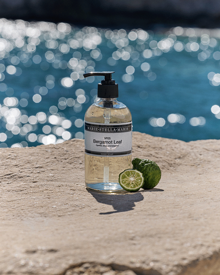 Marie-Stella-Maris No.05 Bergamot Leaf limited edition summer scent hand soap 250 ml, displayed on a sunlit stone surface by the sea with fresh bergamot and sparkling water in the background.