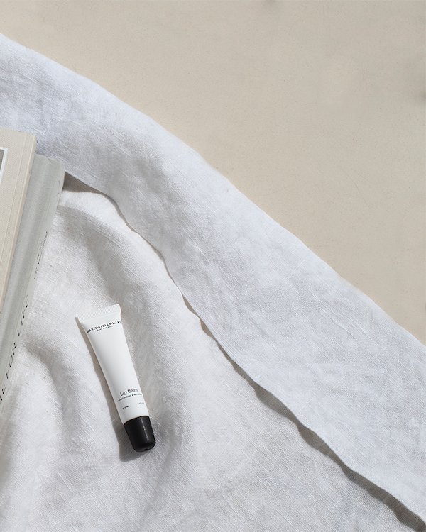 Marie-Stella-Maris lip balm 10 ml tube with a black cap placed on soft white linen in natural daylight.