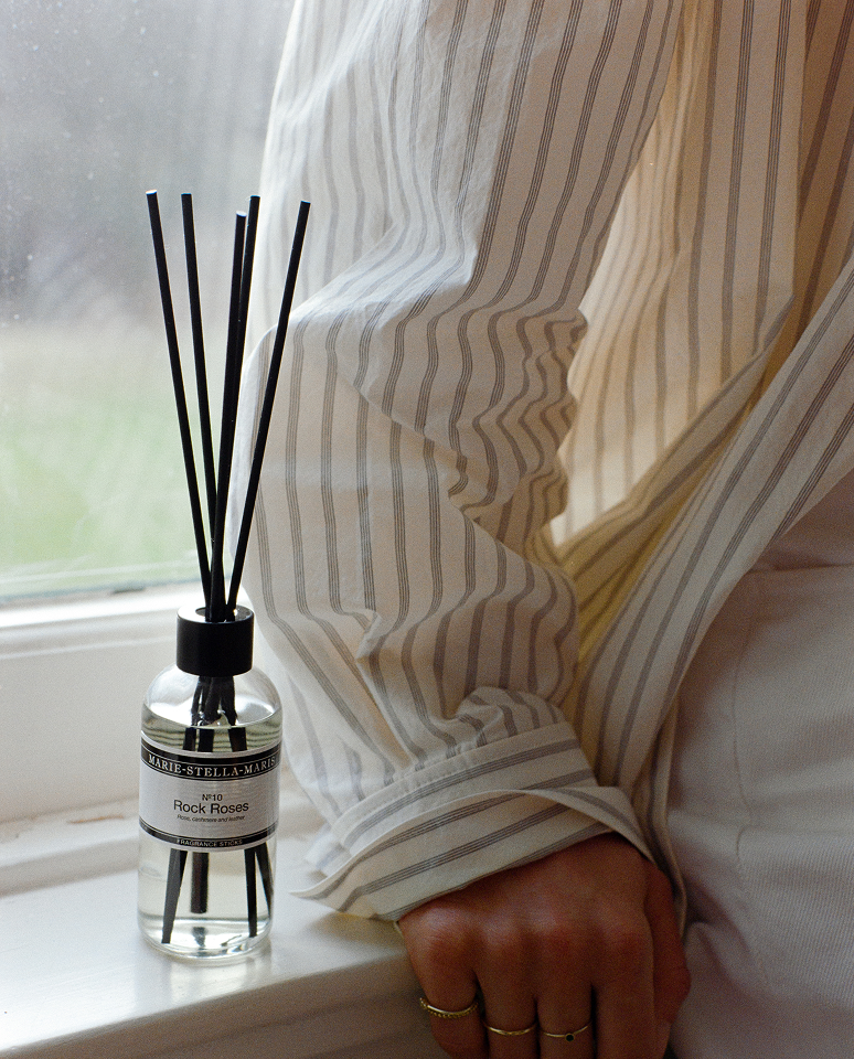 Marie-Stella-Maris Rock Roses fragrance sticks by a window with a model hand next to it