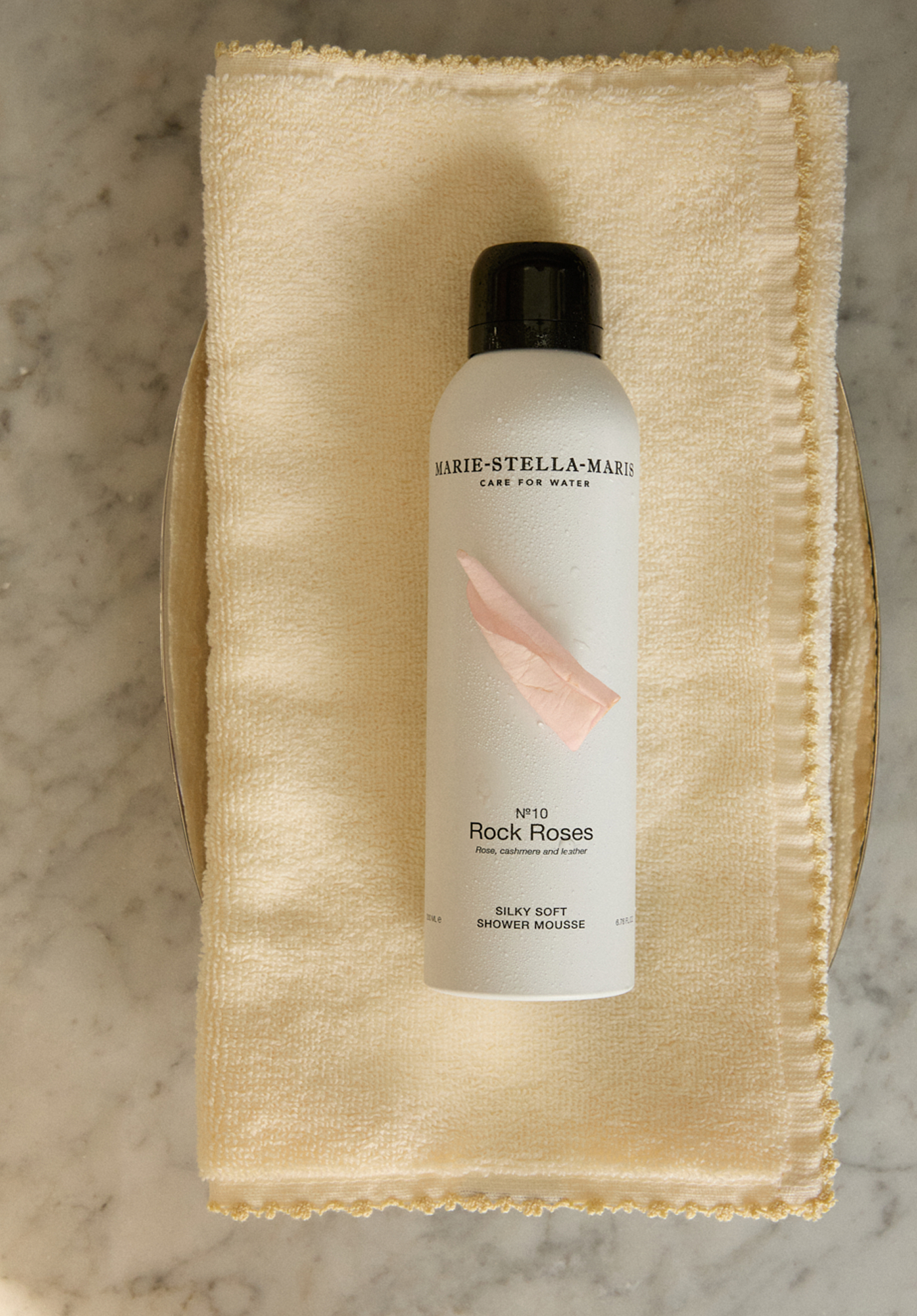 Marie-Stella-Maris Rock Roses shower mousse on a yellow towel with pink flower on top of it
