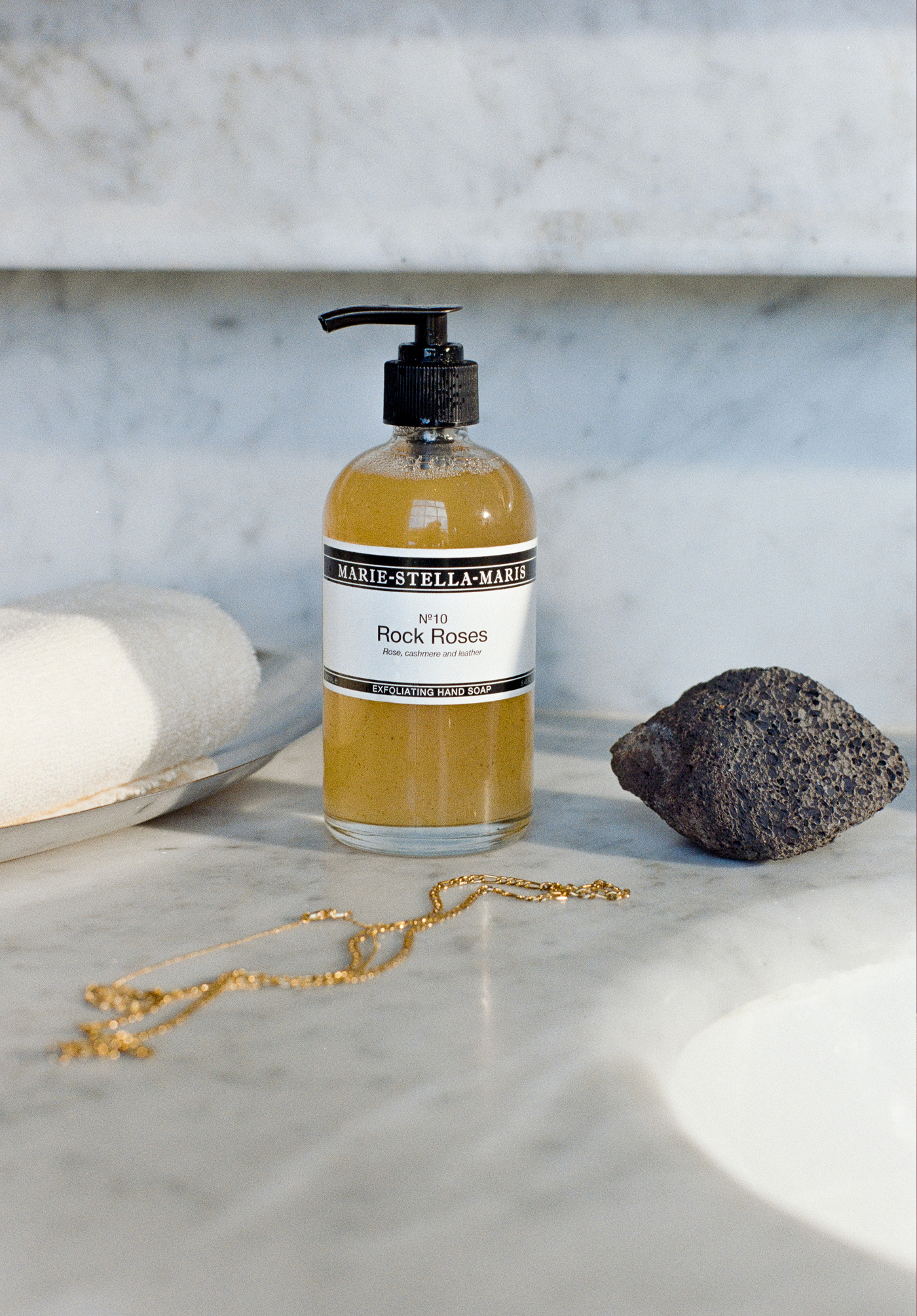 Marie-Stella-Maris Rock Roses hand soap with necklace, rock and towel on marble background