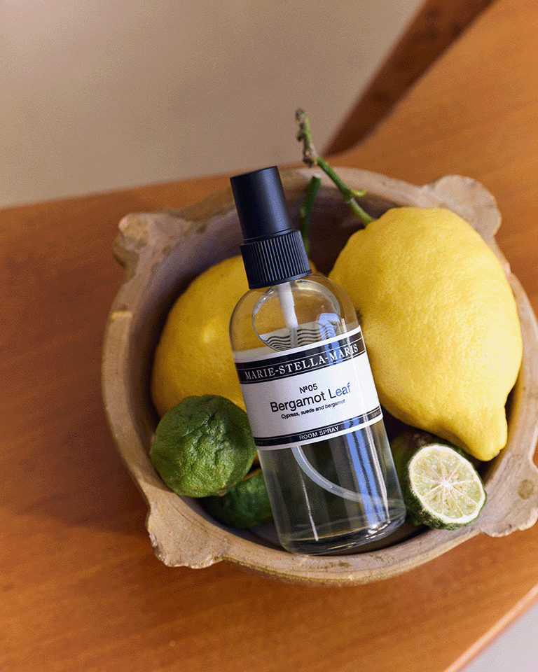 Marie-Stella-Maris No.05 Bergamot Leaf limited edition summer scent room spray 100 ml, placed in a wooden bowl with fresh citrus fruits including lemons and bergamot, styled in a warm indoor setting.