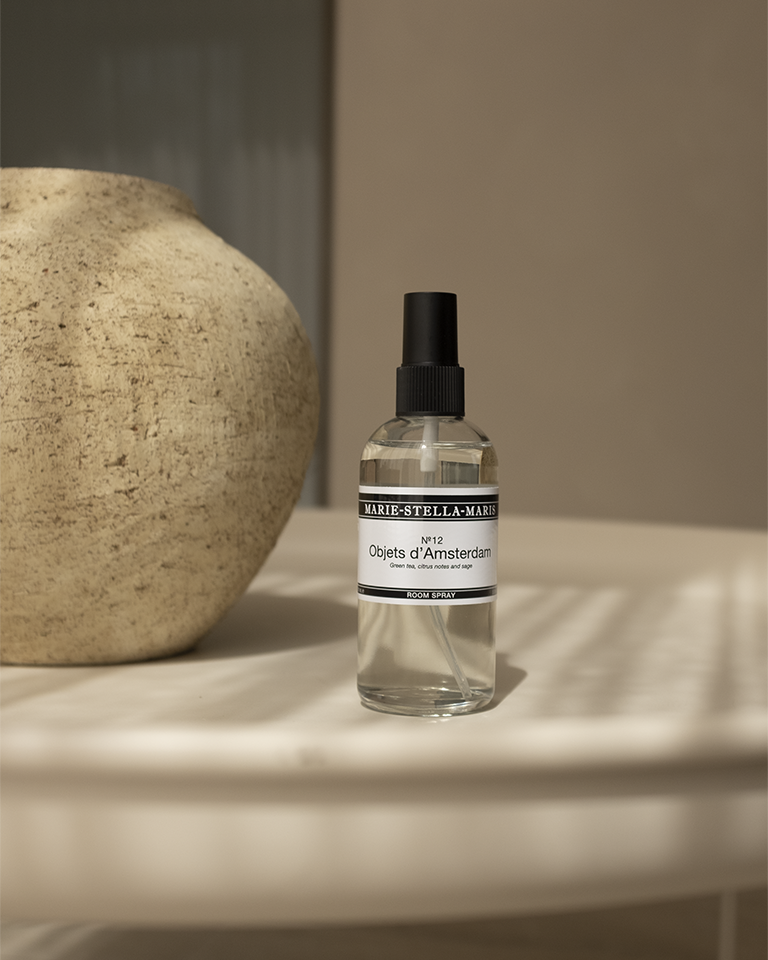 Marie-Stella-Maris Objets d'Amsterdam room spray 100 ml on a surface with a stone object in the background.